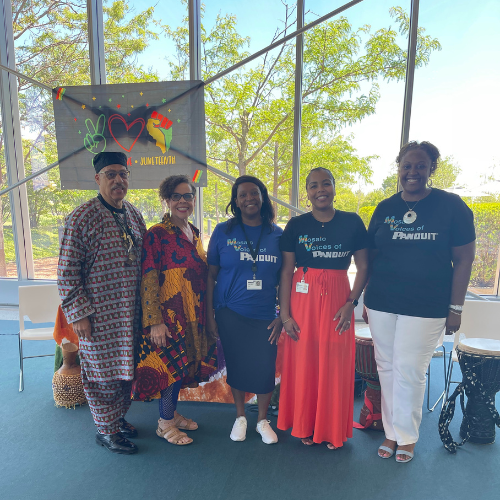 Group of male and female black adults with two in colorful robes, standing together and smiling