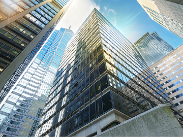 Skyscraper office buildings in city during the day looking up from ground level.