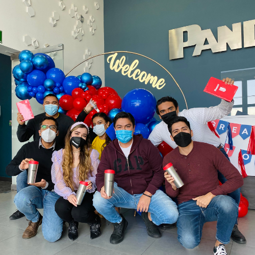 Employees in masks squatting with red and blue balloons behind them