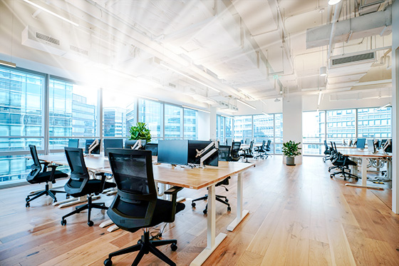 a modern open office space with lots of windows, desks, and computer monitors.