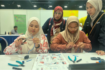 Three women sitting and working on cables