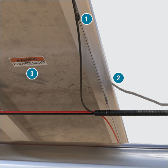 DC power wires suspended in a cable bundle from the back of a solar panel array 