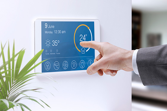 Digital building control panel with a finger adjusting the temperature