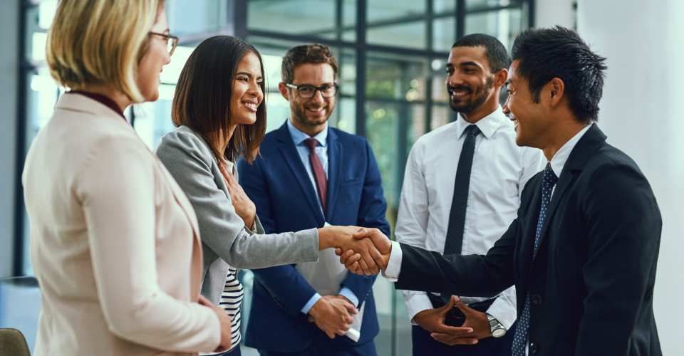 Group of men and women smiling and shaking hands
