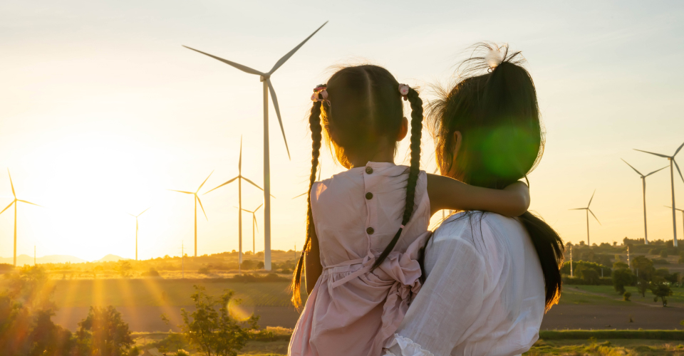 Woman holding child looking at wind turbines